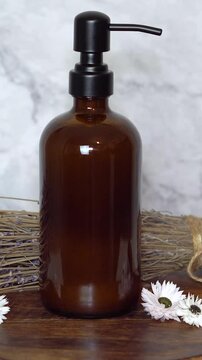 Amber glass shampoo bottle with dry lavender flowers on dark wooden board and marble background. Natural beauty flat lay with rustic, eco-friendly, and calming herbal haircare elements.