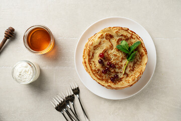 Large pancakes on a light stone background are served by a female cook, top view, home cooking, Maslenitsa, Easter