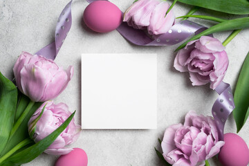 Happy Easter greeting card mockup, colored easter eggs and fresh tulips flowers, blank paper card mock up with copy space