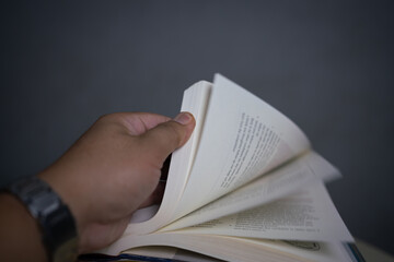 A close-up hand flipping through pages of an open book, highlighting motion and texture. This image represents curiosity, knowledge, and exploration. Perfect for education and literature themes.