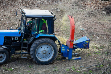 A tractor with a wood chipper is processing wood waste. This machinery allows for efficient cleanup...