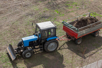 tractor with trailer is transporting a van filled with debris. Construction waste is being removed using machinery that makes heavy work fast and efficient.
