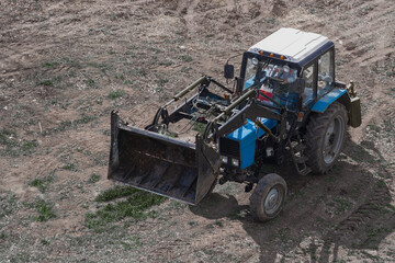 The construction loader is on an open area under the sun. The machinery with an elevated bucket in an open space is a clear demonstration of a professional approach to landscaping.