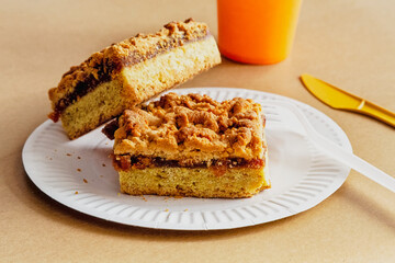 An appetizing pie filled with jam and crumbs, surrounded by disposable tableware. A symbol of quick homemade meals and delicious treats.