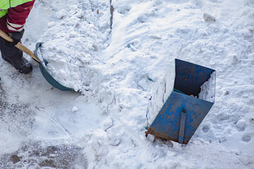 Manual snow removal: a municipal worker in a safety vest clears the sidewalk, tackling the aftermath of a snowfall.