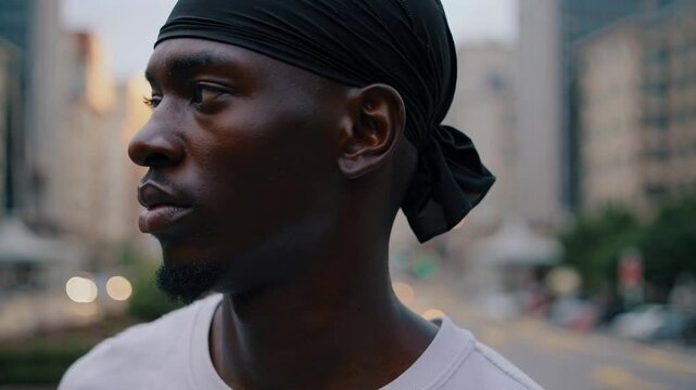 Urban portrait of young Black man with durag in city evening light