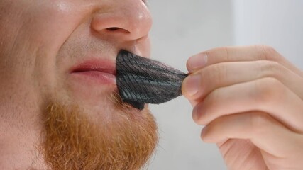 Man Peeling Off Black Hostage Tape Breathable Mouth Tape from Lips Showing Adhesive Stretch in Detailed Close-Up for Snoring Prevention Concept