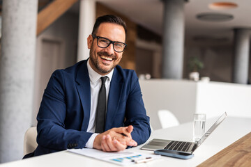 Fototapeta premium Smiling Businessman in Formal Attire Sitting at Office Desk