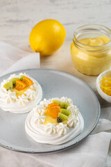 Lemon Curd and Berries Pavlova dessert on light beige background. Vertical