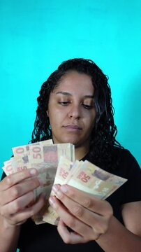 Brazilian brunette curly latina woman counting Brazilian reais money