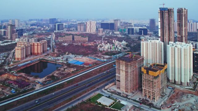 Hyderabad under construction buildings beside nehru outer ring road with vehicles and tallest skyscraper at Kokapet, financial district, telangana, india. day time, pan shot, drone shot, 4k.