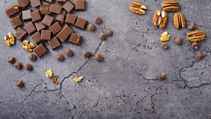 Chocolate squares and nuts on a gray background