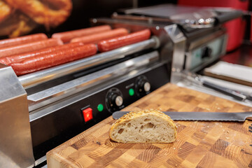 Hot dog machine closeup. Sausages grill at hot-dog maker. Professional equipment for hotdog preparation.