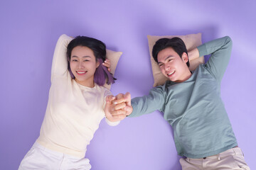 Obraz premium Happy couple relaxing together on a purple background holding hands and enjoying each other's company
