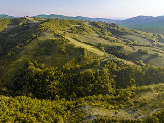 Fototapeta premium Aerial Drone View of the Idyllic Tuscan Countryside with Rolling Hills, Vineyards, Olive Groves, and Farmhouses Under a Clear Summer Sky in the Heart of Rural Italy