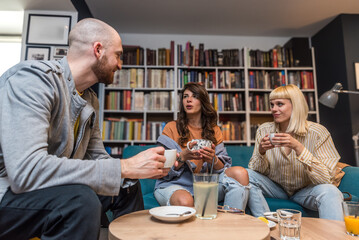 Happy young university students studying with books in library. Group of educated intelligent people in college library, drinking coffee and talking about project. Friends weekend activities.