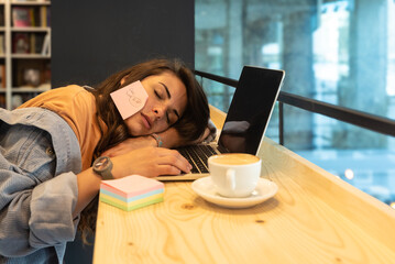 Young freelance business woman, tired and exhausted of work, working lazy in library on laptop...