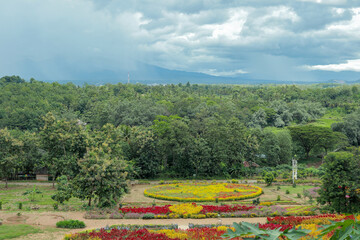 Colorful flower garden with lush greenery and mountain backdrop. High-angle view of a vibrant flower garden with various colorful flowers arranged in intricate patterns.