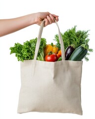 Hand holding tote bag filled with fresh produce from farmer's market on white backdrop.
