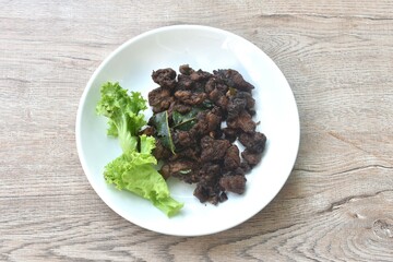 fried crispy salty fermenting beef meat with lemon leaf and lettuce on plate 