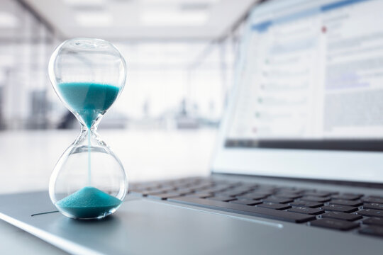 Hourglass on laptop computer keyboard concept for time management