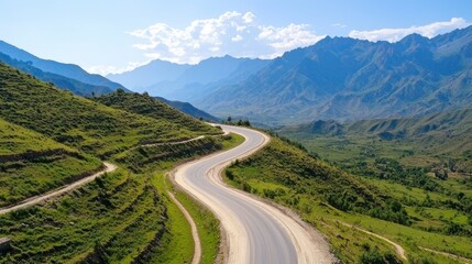 Fototapeta premium Serene Curved Road Through Lush Green Mountains Under Blue Sky