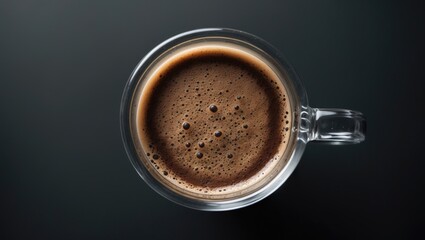 Top view close-up of espresso coffee foam in glass on black desk floor, bubble surface of the hot beverage