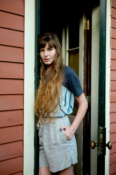 Woman with long hair standing in a doorway, wearing casual summer clothing. New Orleans, Louisiana, USA