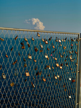 Metal fence over the ocean adorned with numerous padlocks under a clear blue sky. Split, Croatia