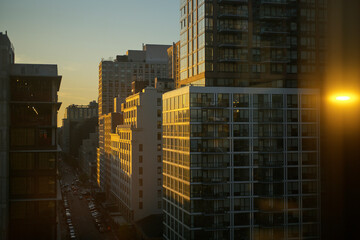 Sunset light reflecting on high-rise buildings along a busy city street. New York City, NY, USA