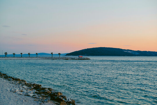 A tranquil coastal scene at sunset, with calm water, a distant island, and a vivid horizon. Split, Croatia