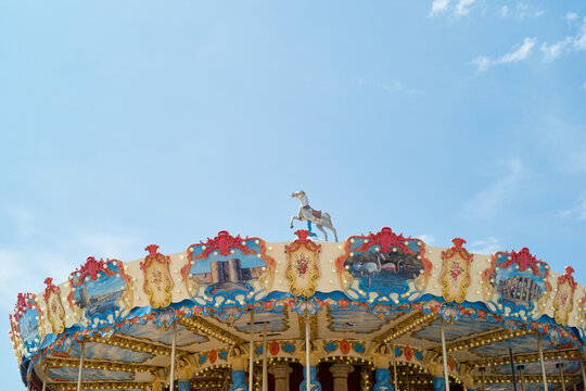 Colorful vintage carousel against a bright blue sky with fluffy white clouds. France