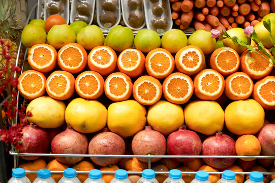 Freshly sliced oranges and an array of fruits displayed on a market stand.