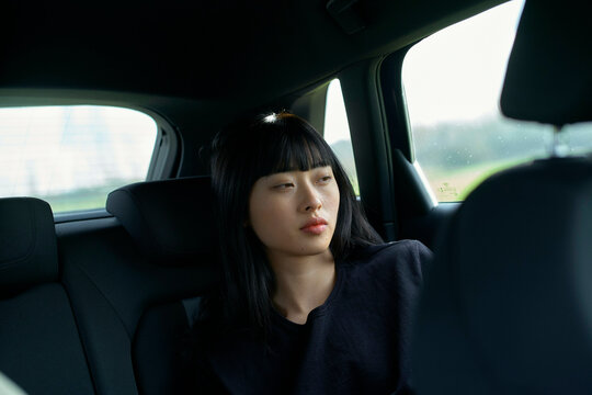 Woman with black hair gazes out a car window during a daytime drive. Brandenburg, Germany