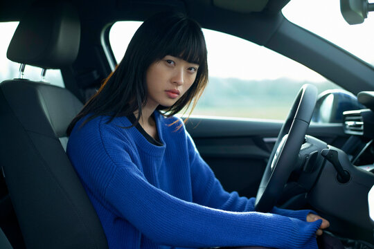 Woman in a blue sweater seated in a car, looking towards the camera with a calm expression. Brandenburg, Germany