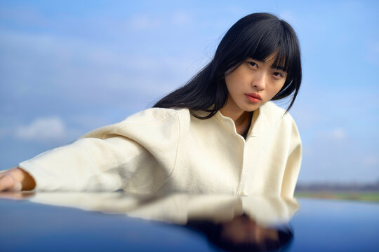 Woman in a white sweater gazes intensely with a blue sky background. Brandenburg, Germany