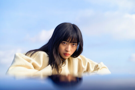 Young woman in a white sweater gazing intently against a sky background. Brandenburg, Germany