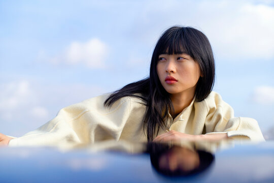 Woman in a white blouse lying down, gazing thoughtfully into the distance. Brandenburg, Germany