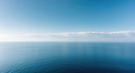 Obraz premium Expansive panorama of a clear sky setting for travel inspiration at the ocean with radiant sunlight and charming clouds.