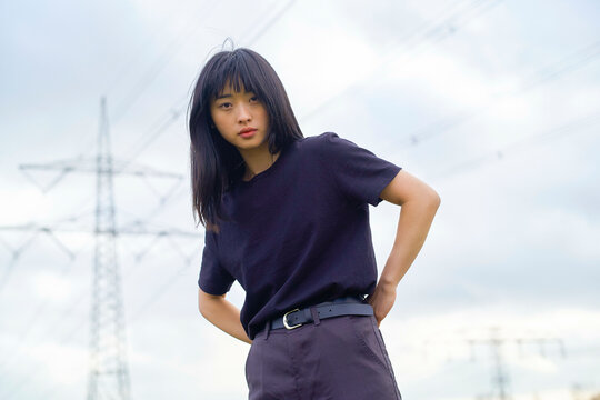 Young woman in a black shirt stands outdoors with power lines in the background. Brandenburg, Germany