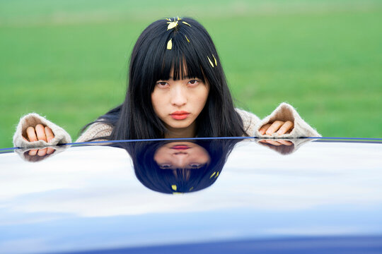 Woman and her reflection on a shiny car roof. Brandenburg, Germany