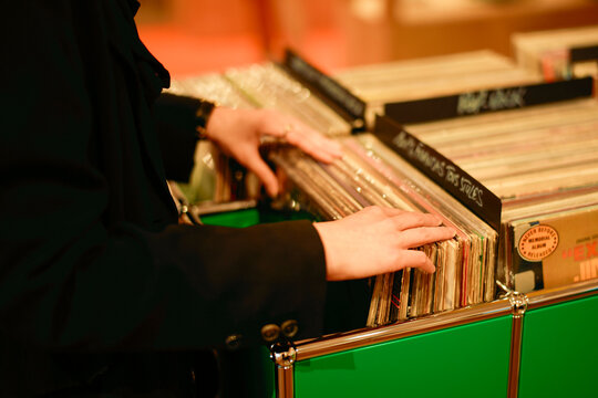 Person browsing a collection of vinyl records in a green box at a store.
