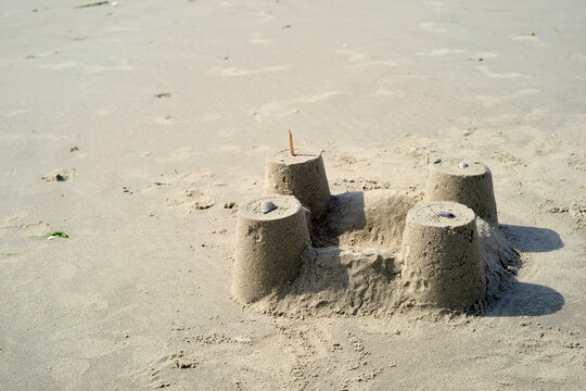 Sandcastle with four towers and a stick on a sunny beach. Normandy, France