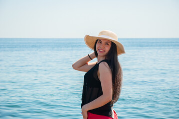 Woman enjoying a sunny day at the beach in a wide-brimmed hat. Happy summer days, travel and vacation concept