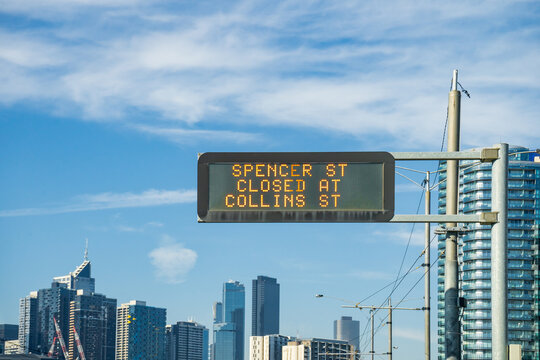 Looking up an overhead traffic sign set against a city skyline