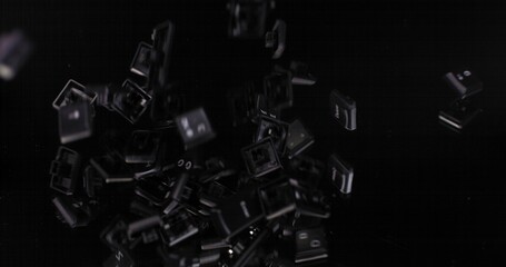 A lot of computer keys from a keyboard with latin letters and numbers falling down, slow motion on a black background