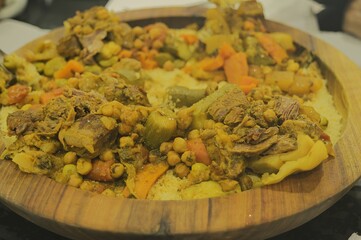 couscous with vegetables and meat on a wooden plate (Kesaa), an Amazigh culinary heritage dish of Morocco and the Maghreb 