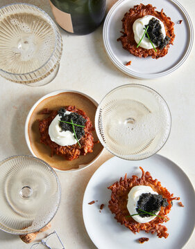Caviar on potato pancakes with champagne on table