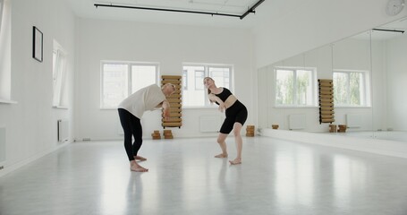 A guy and a girl of European appearance, dressed in sportswear, make synchronized movements while...