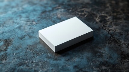A sleek, minimalist white box rests against a textured dark blue surface, creating a striking contrast of color and simplicity.